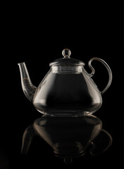 Beautiful transparent glass teapot close-up isolated on black background.