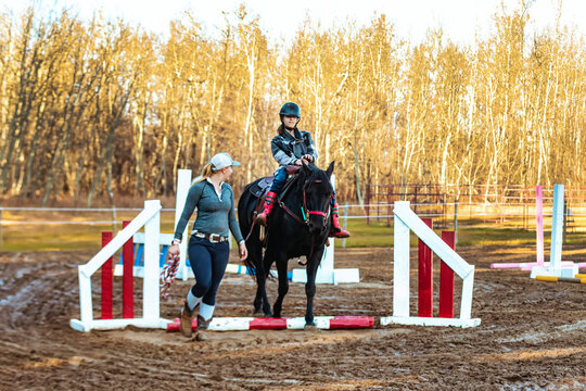 A trainer working with a young girl with Cerebral Palsy during a Hippotherapy session; Westlock, Alberta, Canada