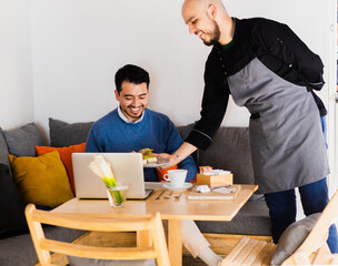 Person in a restaurant receiving food by the chef, a young Caucasian man smiling.
