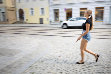 Obraz premium Blind woman walking on city streets, using her white cane to navigate the urban space better and to get to her destination safely