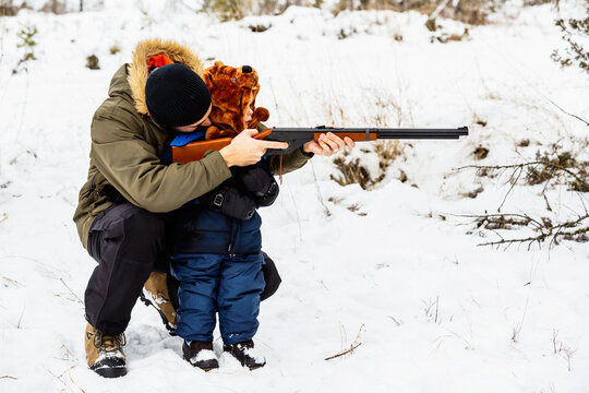 Father Teaching A Young Son How To Shoot A Rifle In Winter At A Mountain Resort; Fairmont Hot Springs, British Columbia, Canada