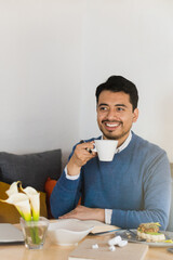Handsome young man sitting in a coffee shop enjoying a cup of coffee. Copy space.