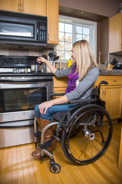 Young disabled woman cooking in the kitchen at home; Spruce Grove, Alberta, Canada