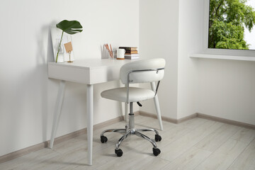 Comfortable workplace with white desk near wall at home