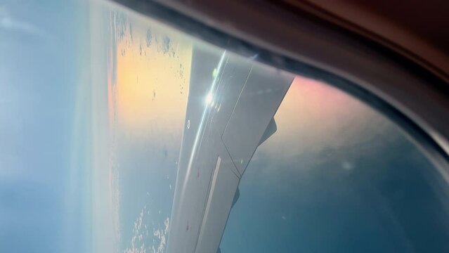Vertical footage through illuminator of the wing of the Scandinavian airlines aircraft when landing in clear sunny weather, clouds, islands in the sea