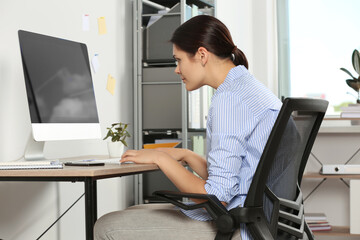 Young woman with bad posture sitting at workplace in office. Symptom of scoliosis