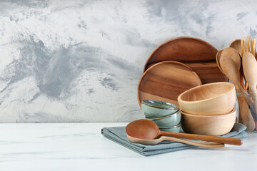 Different dishware and utensils on white marble table against textured wall. Space for text