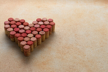 Heart made of wine bottle corks on textured table. Space for text
