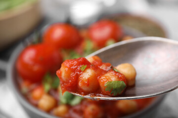 Spoon with delicious chickpea curry, closeup view