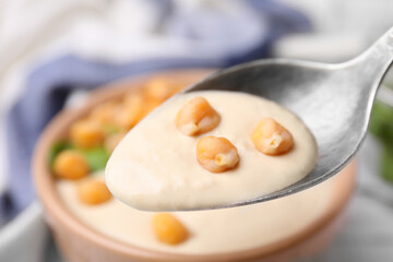 Eating tasty chickpea soup on table, closeup