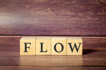 word flow made with wooden block and brown background