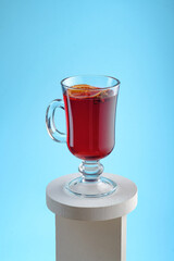 Mulled wine with dried orange, cinnamon sticks and cloves isolated on a blue background. Winter traditional alcoholic hot drink based on wine.