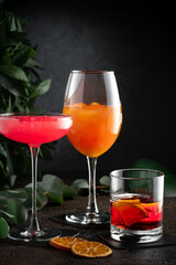 A set of three multi-colored cocktails on a dark background. Alcoholic drinks in glasses
