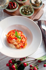 Spaghetti in tomato sauce with basil and parmesan in a white plate. Italian pasta recipe with tomatoes