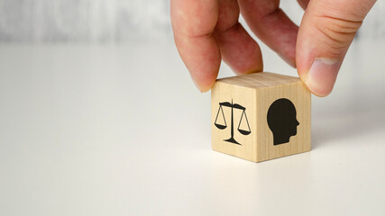 Business ethics concept. Hand flip ethics inside a head symbols in wooden cubes on dark background...