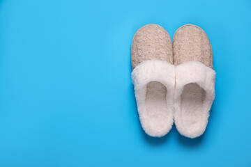 Pair of beautiful soft slippers on light blue background, top view. Space for text