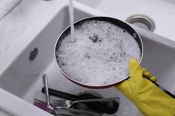 Woman washing dirty dishes in kitchen sink, closeup