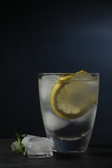 Shot of vodka with lemon, ice and mint on black table