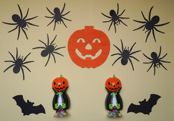 Scary Halloween figurines stand on a light background in close-up, behind hangs terrible pumpkin. Cute character in monster costume. Halloween concept. Holiday decorations toys