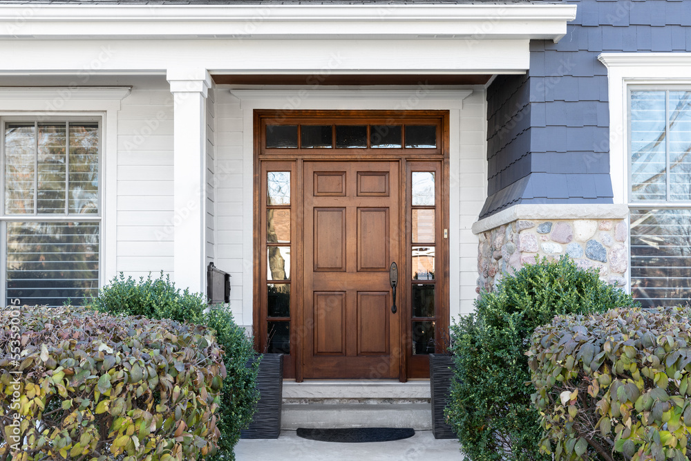 Wall mural A wooden front door, surrounded by windows, with white, blue, and stone siding.