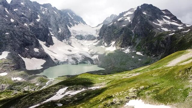 Quadrocopter shoot to blue lake between high mountains in the wild nature. The beautiful view from sky with drone