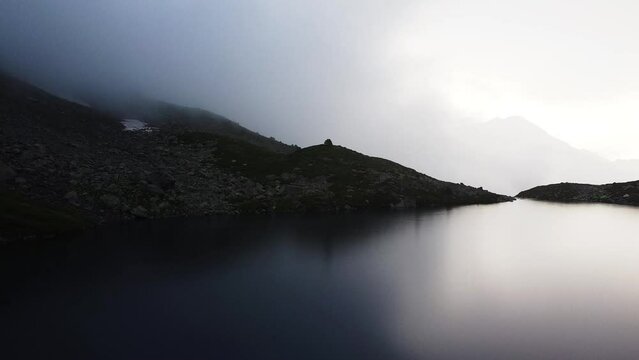 Quadrocopter shoot to blue lake between high mountains in the wild nature. The beautiful view from sky with drone