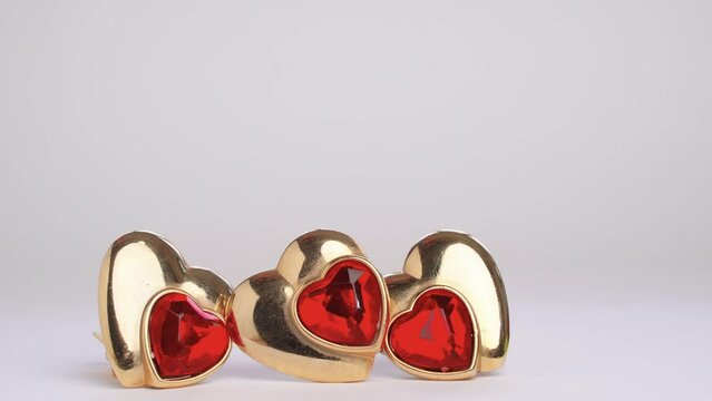 Hand adds heart shaped earring ruby to pair. Polyamory. Threesome. Infidelity