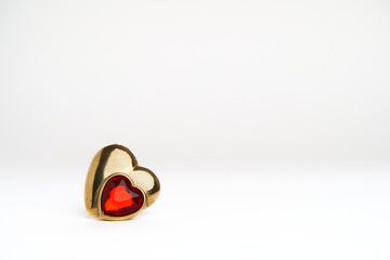 Single in Valentine's day concept. Heart shaped golden jewel with ruby isolated over white background