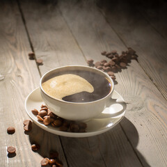 White cup of hot coffee with steam on a wooden table backlit