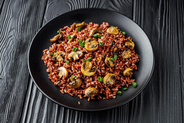 delicious red rice with mushrooms on a black wooden rustic background