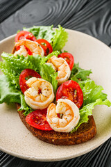 delicious Italian bruschetta with shrimps on a black wooden rustic background