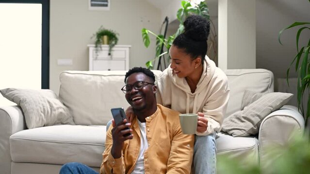 Multiracial couple using smartphone while sitting on the couch at home