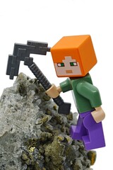 Fototapeta premium LEGO Minecraft figure of Alex with iron pickaxe on Chalcopyrite mineral rock, white background. 