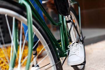 Naklejka premium View of a man with prosthetic legs and white sneakers. Sitting on his bicycle