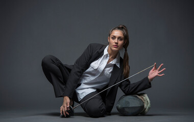 girl with a fencing rapier and a fencing helmet in a black suit