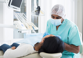 Obraz na płótnie Canvas Male dentist treating female patient in dental office