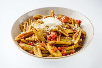green cavatelli pasta with spinach in tomato sauce on a white background