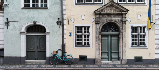 Vintage bicycle parked in front of old house. Facade of building in Old town of Riga, Latvia. European architecture. Ukrainian flag on facade.