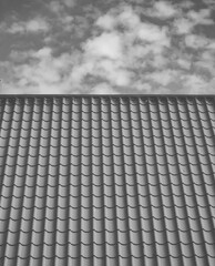Red tiled roof. CLouds in blue sky. Close-up.