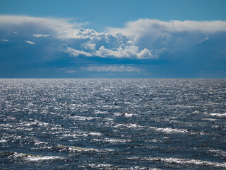 Beautiful seascape. Cloudy sky. Reflection of sunlight on sea waves.