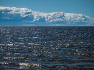 Beautiful seascape. Cloudy sky. Reflection of sunlight on sea waves.