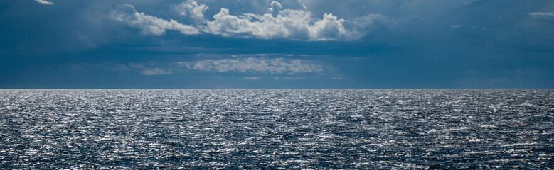 Beautiful seascape. Cloudy sky. Reflection of sunlight on sea waves.