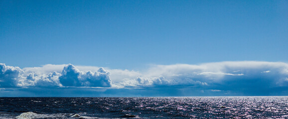 Beautiful seascape. Cloudy sky. Reflection of sunlight on sea waves.