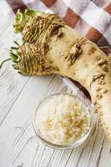 aromatic horseradish root on a white rustic wooden background
