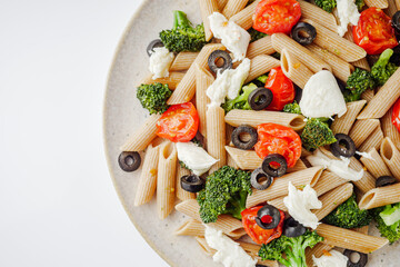delicious penne wheat pasta with tomatoes, broccoli and mozzarella on a white background