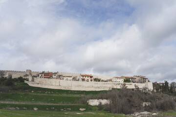 Cuellar village and its wall surrounded by green fields and blue sky with some clouds. Spain