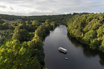 Fototapeta premium Sunset on the river Míño in the town of Lugo with some trees surrounding the river and a boat crossing it at sunset.