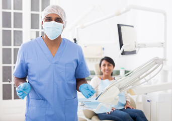 Professional dentist standing in office with patient background