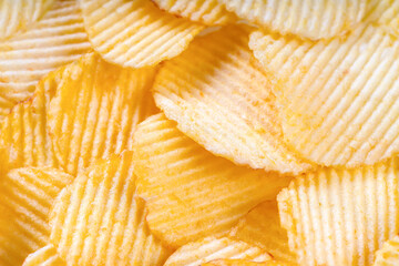 Yellow crispy ridged potato chips close up. Food background, banner, header, wallpaper.