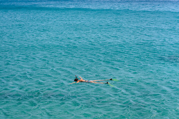 Sea in Greece with a silhouette of a diver in flippers on the surface of the water